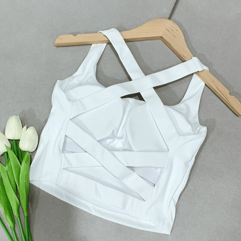 White cross back women's running tank top on wooden hanger with tulips